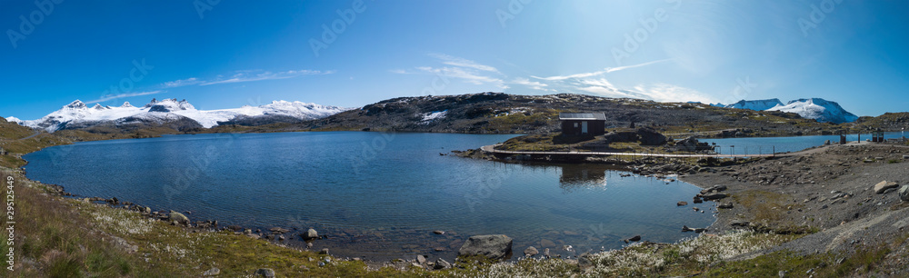Wide panoramatic view from Sognefjellshytta with blue glacier Fantesteinsvatnet lake along National scenic route Sognefjellet between Skjolden in Western Norway. Autumn blue sky.