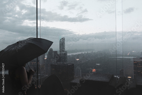 Young woman watching central park during a rainy day from the top of a skyscraper