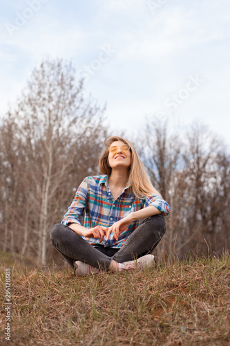 Happy young woman sitting on the hill in autumn.