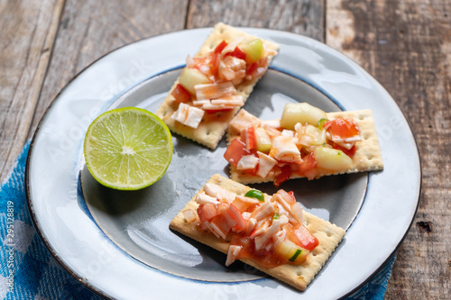 Surimi crab ceviche with cucumber and tomato on wooden background