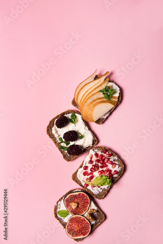 Trendy sandwiches with fresh fruits, like pomegranate, figs, mulberry and pears. Healthy food concept with different sandwiches with vibrant color style.