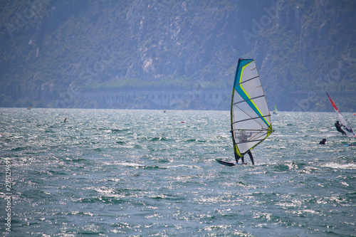 Windsurfer at Lake Garda glistening in the sun  with the street tunnels in the distance (Torbole, Italy)