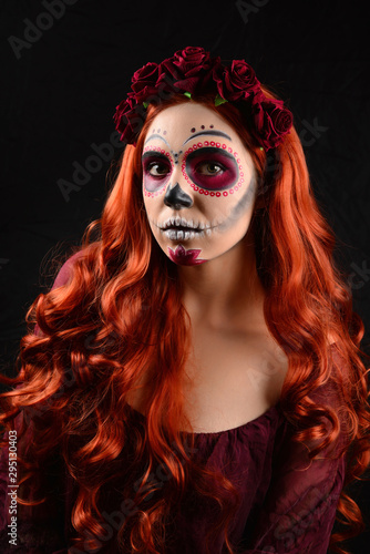 Woman with sugar skull makeup and red hair isolated on black background. Day of the dead. Halloween.