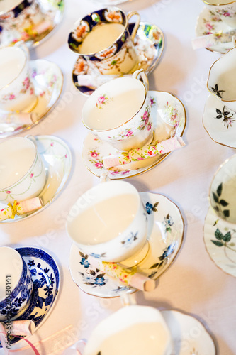 Decorative china teacups and matching saucers on white table cloth.