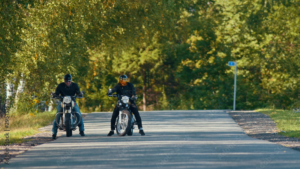 Two bikers on their bikes are standing on the road Two bikers on their bikes are standing on the road