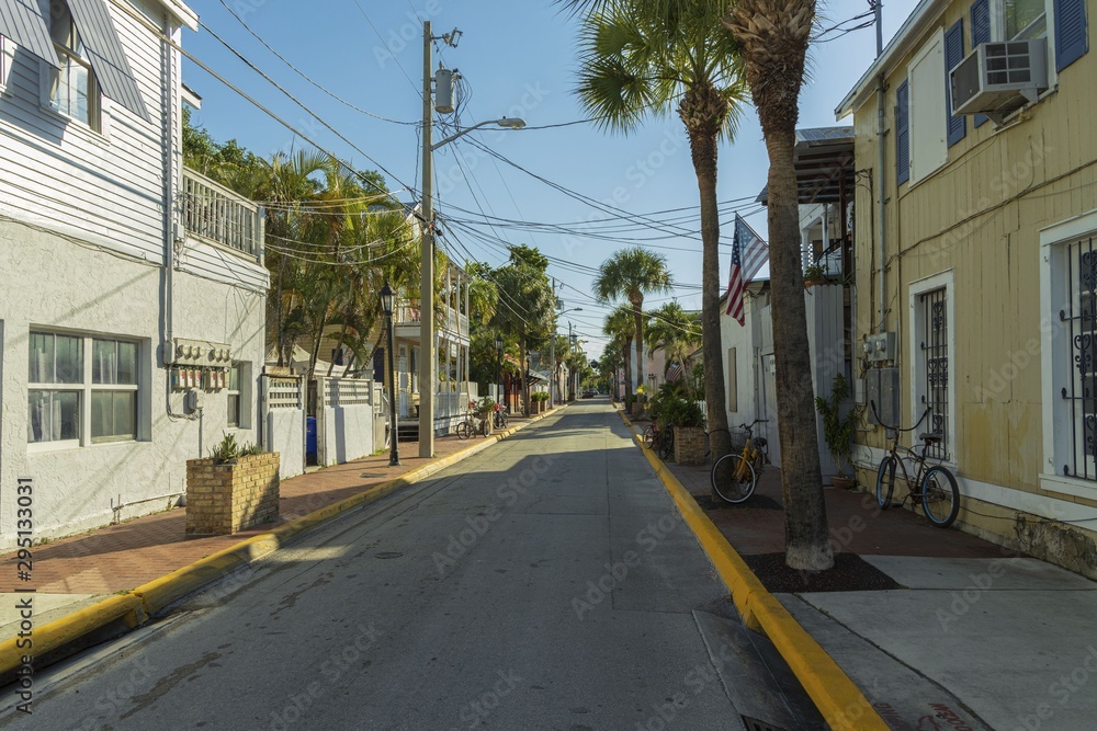 Beautiful street landscape view of one of streets in Key wet, Florida. Light houses and green palm trees on blue sky background.