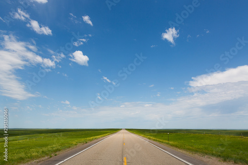 Tableau sur toile Empty two lane highway beneath calm blue sky.