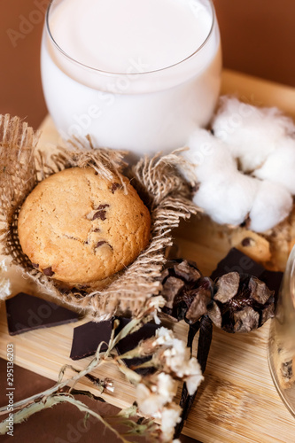 Shortbread chocolate cookies and a glass of milk on a brown background.  Milk chocolate with nuts and cookies.