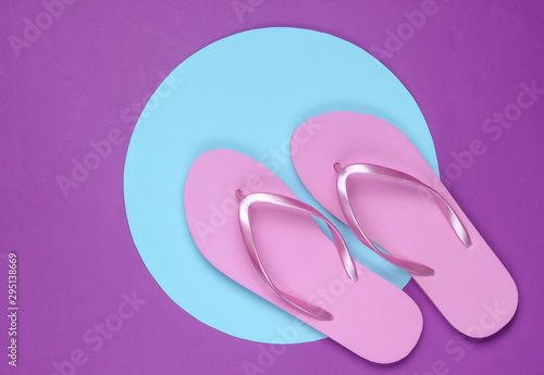 Pink flip flops on purple background with blue pastel circle. Minimalistic vacation on the beach concept. Summer time