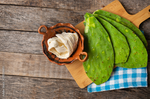 Raw nopal cactus and oaxaca cheese on wooden background