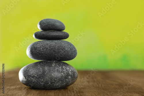 Stack of stones on table against blurred green background  space for text. Zen concept