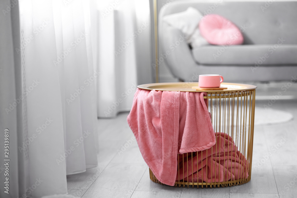Side basket table with cup of coffee and blanket in modern room interior - obrazy, fototapety, plakaty 