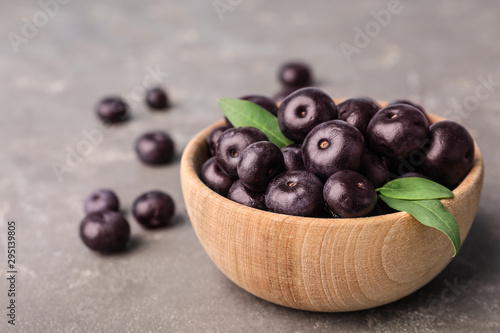 Bowl of fresh acai berries on grey stone table, closeup view. Space for text