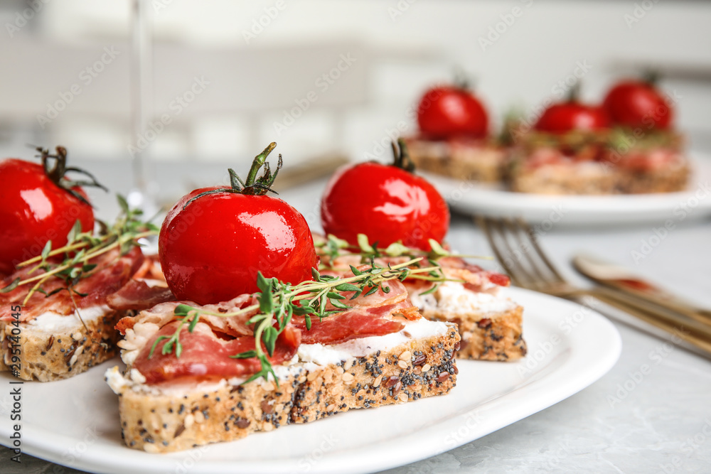 Plate of delicious bruschettas with prosciutto on grey kitchen table Plate of delicious bruschettas with prosciutto on grey kitchen table