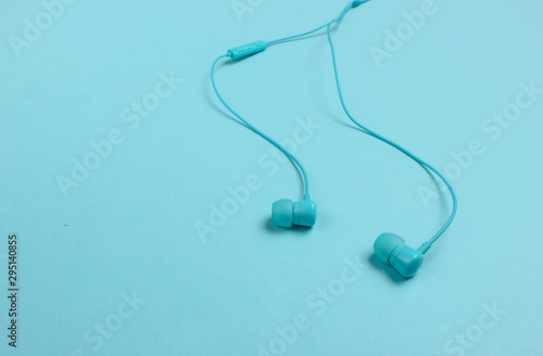 Wired earphones on blue background close-up. Music lover