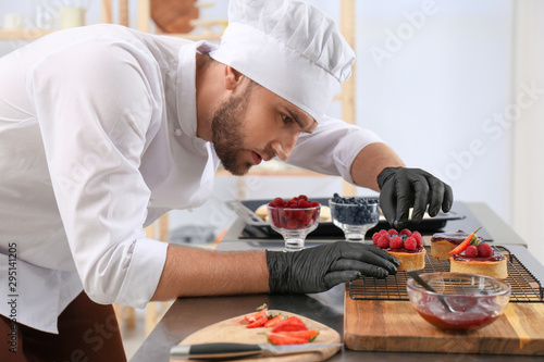 Bild auf Leinwand Male pastry chef preparing desserts at table in kitchen