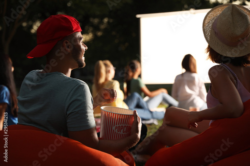 Fotografie, Obraz Young couple with popcorn watching movie in open air cinema