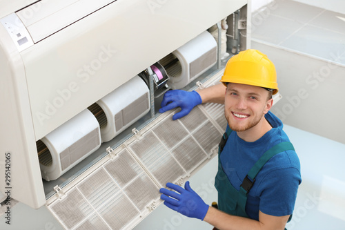 Cuadro en lienzo Professional technician maintaining modern air conditioner indoors
