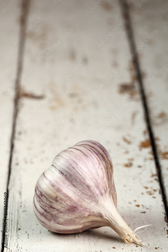 Garlic bulb on peeling paint plank table, copy space.