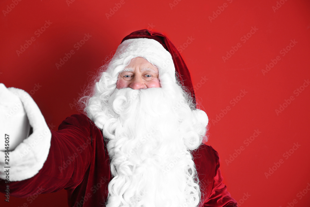 Authentic Santa Claus taking selfie on red background