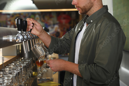 Bartender pouring fresh beer into glass in pub  closeup