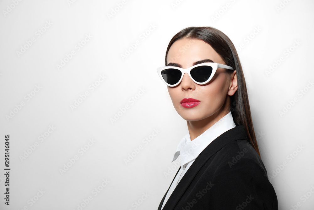 Young businesswoman in stylish sunglasses on light background, space for text Young businesswoman in stylish sunglasses on light background, space for text