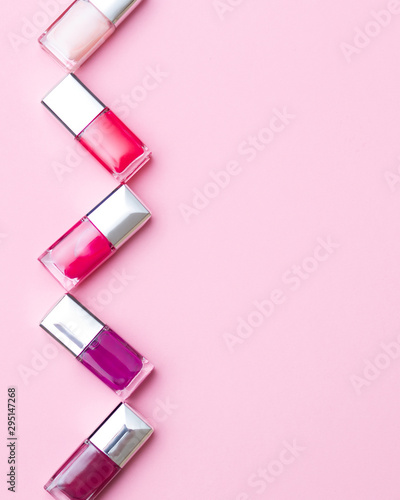 nail polishes of different colors are built on a pink background concept flat lay