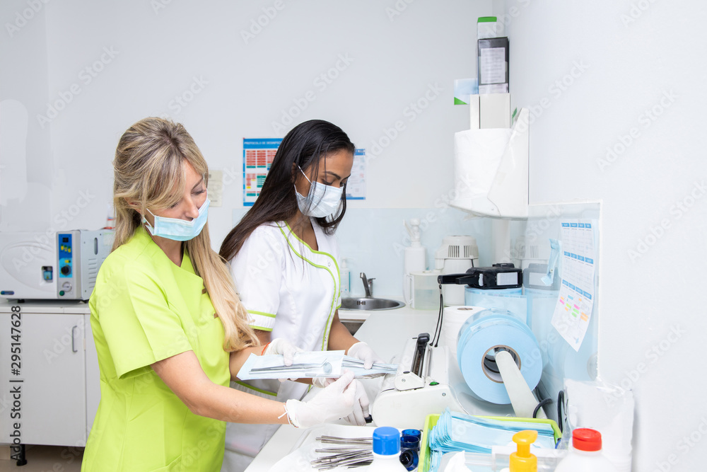 two dentists doctors in the sterilization room of a dental clinic. They are working sterilizing the material two dentists doctors in the sterilization room of a dental clinic. They are working sterilizing the material