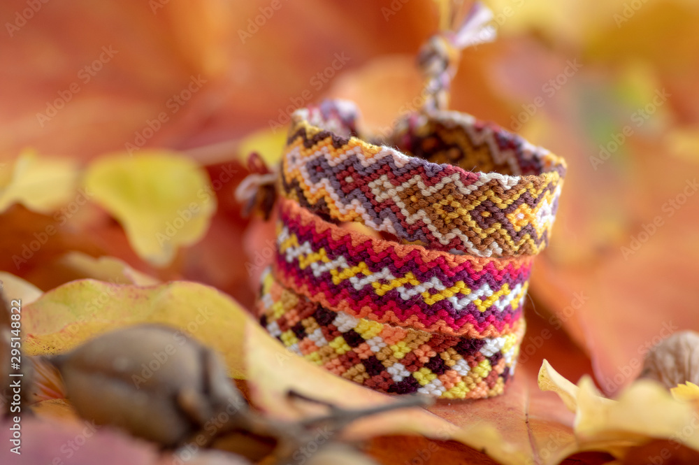 Autumn still life, group of handmade homemade colorful natural woven bracelets of friendship on dry color leaves