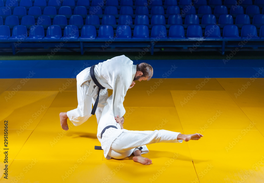 Martial arts. Sparing Portners. Sport man and woman in white kimono train judo throws and captures in the sports hall Martial arts. Sparing Portners. Sport man and woman in white kimono train judo throws and captures in the sports hall