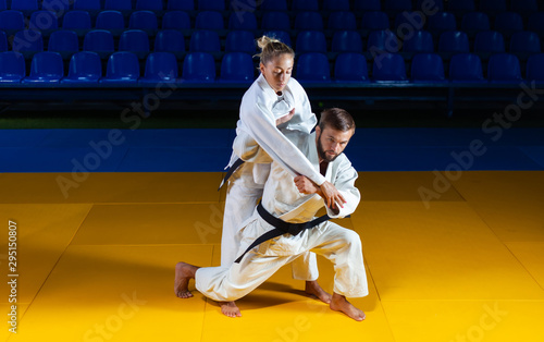 Martial arts. Sparing Portners. Sport man and woman in white kimono train judo throws and captures in the sports hall