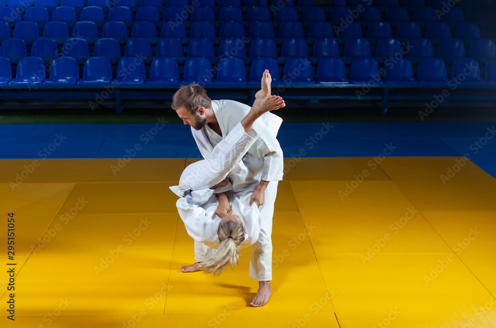 Martial arts. Sparing Portners. Sport man and woman in white kimono train judo throws and captures in the sports hall