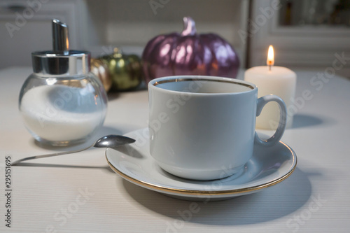 On a light table, a cup of coffee and ceramic pumpkins. Halloween