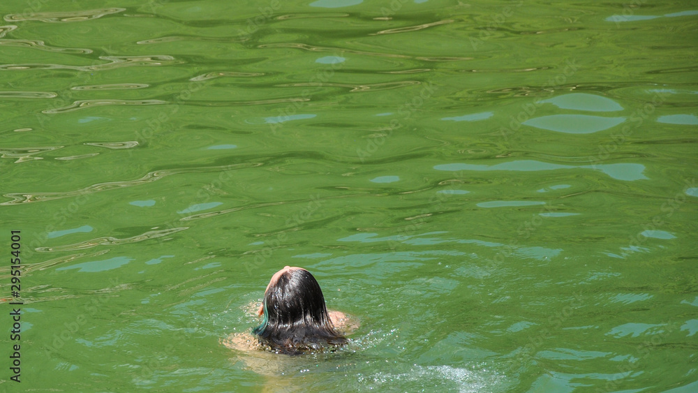 Obraz premium Cabeza de mujer por detrás con pelo mojado dentro del río