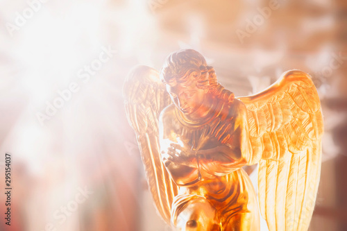 Ancient statue of gold angel in the sunlight. Religion, faith, resurrection concept