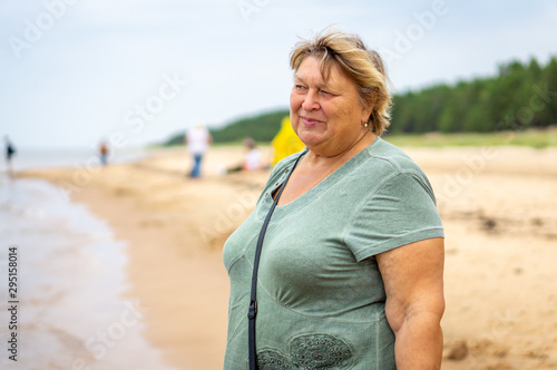 Mature plump woman resting on the beach of the sea.