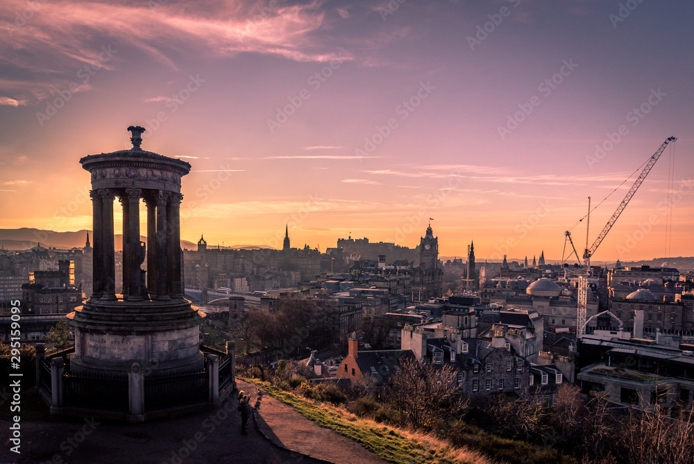 EDINBURGH, SCOTLAND DECEMBER 14, 2018: Beautiful sunset at the Dugald Stewart Monument in the foreground with central Edinburgh cityscape behind including Edinburgh Castle and North Bridge