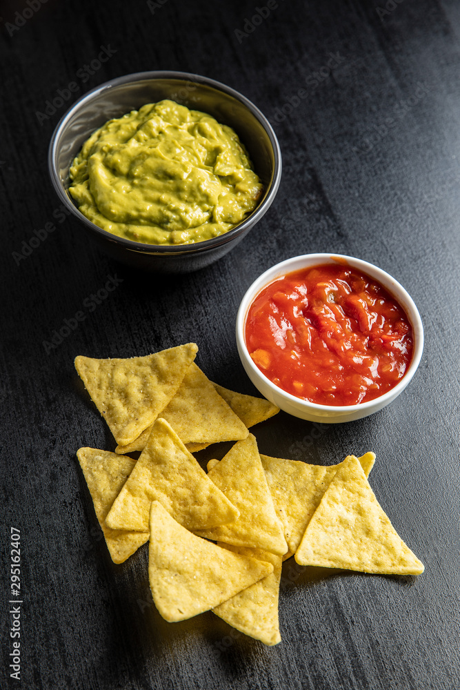 Corn nacho chips with avocado and tomato dip. Yellow tortilla chips and guacamole salsa. Corn nacho chips with avocado and tomato dip. Yellow tortilla chips and guacamole salsa.