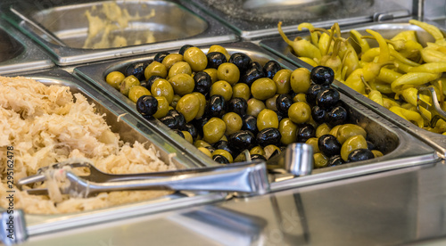 ingredients at a falafel bar with metal vegetable tongs green peppers black olives green olives and cabbage