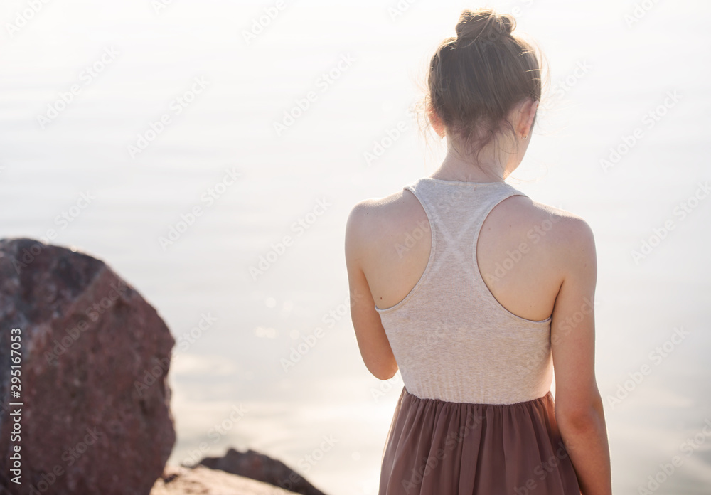 A young girl with a beautiful athletic back. Ballerina near the water.
