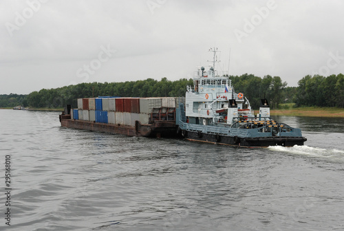 A barge with containers with a tugboat goes along the Yenisei River from the city of Krasnoyarsk to the north, Russia. photo