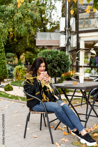 beautiful girl in yellow sweater drinking coffee outside © Uliana