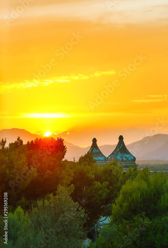 Two church towers over beautiful sunset in the mountains.