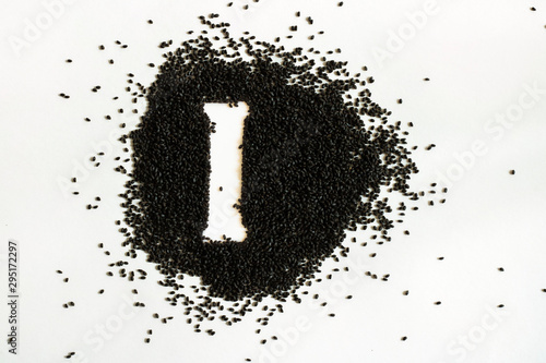 Handful of sweet basil black seeds, letter I uppercase of English alphabet on white background. Black and white. Lettering. Typography. Healthy and super food. Horizontal