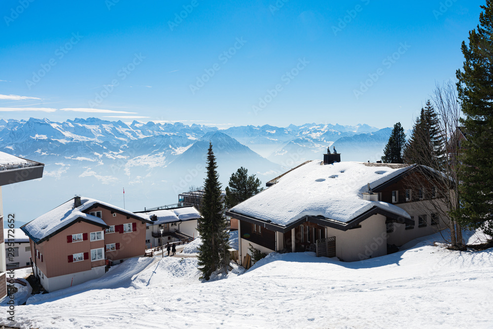 Majestic unique misty blue alpine skyline aerial panorama of Rigi resort. Snow-capped Chalets, hotels, wooden lodging cabins, iced Swiss Alps, blue sky. Mount Rigi, Weggis, Lucerne, Switzerland.