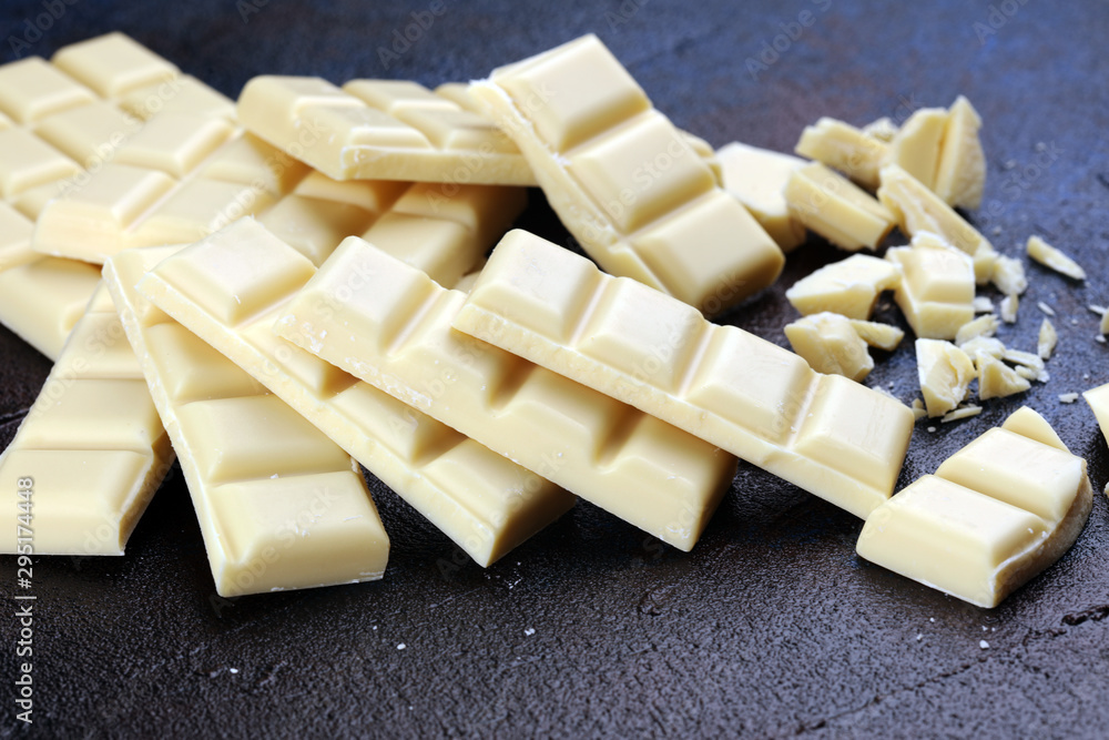 white broken chocolate and cocoa bar. Pieces of white chocolate on rustic background white broken chocolate and cocoa bar. Pieces of white chocolate on rustic background