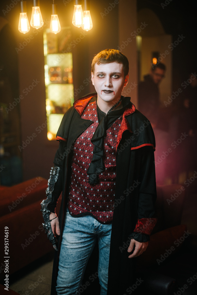 Fototapeta premium Young man in a Halloween costume of Count Dracula with a serious face looks at the camera