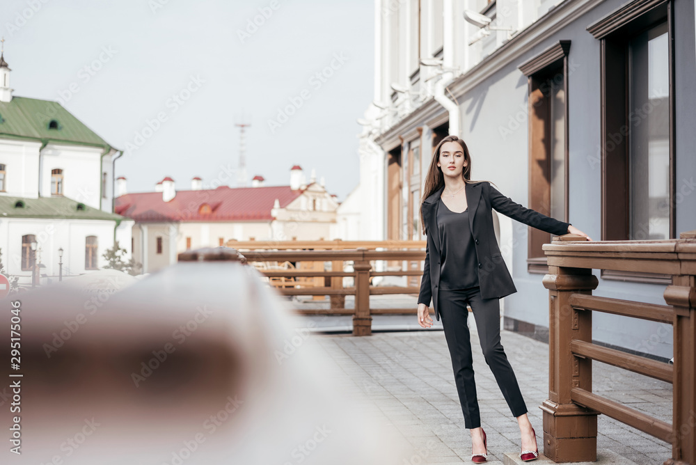 Fototapeta premium Business girl in a black suit against the background of the city
