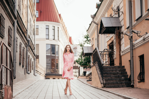 A young, beautiful girl in a pink dress walks through the beautiful streets in the city. Very beautiful portraits of a girl in the city. © majorik0207