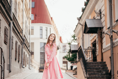 A young, beautiful girl in a pink dress walks through the beautiful streets in the city. Very beautiful portraits of a girl in the city.